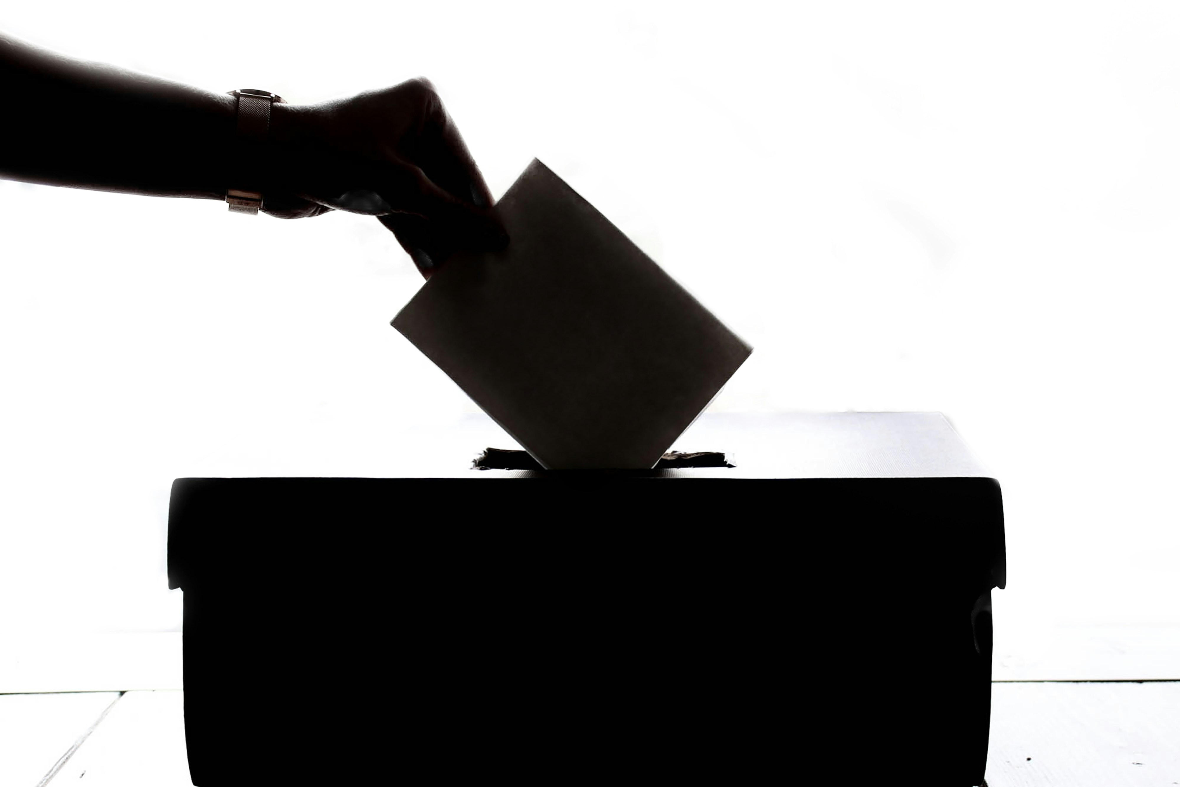 person placing envelope in ballot box