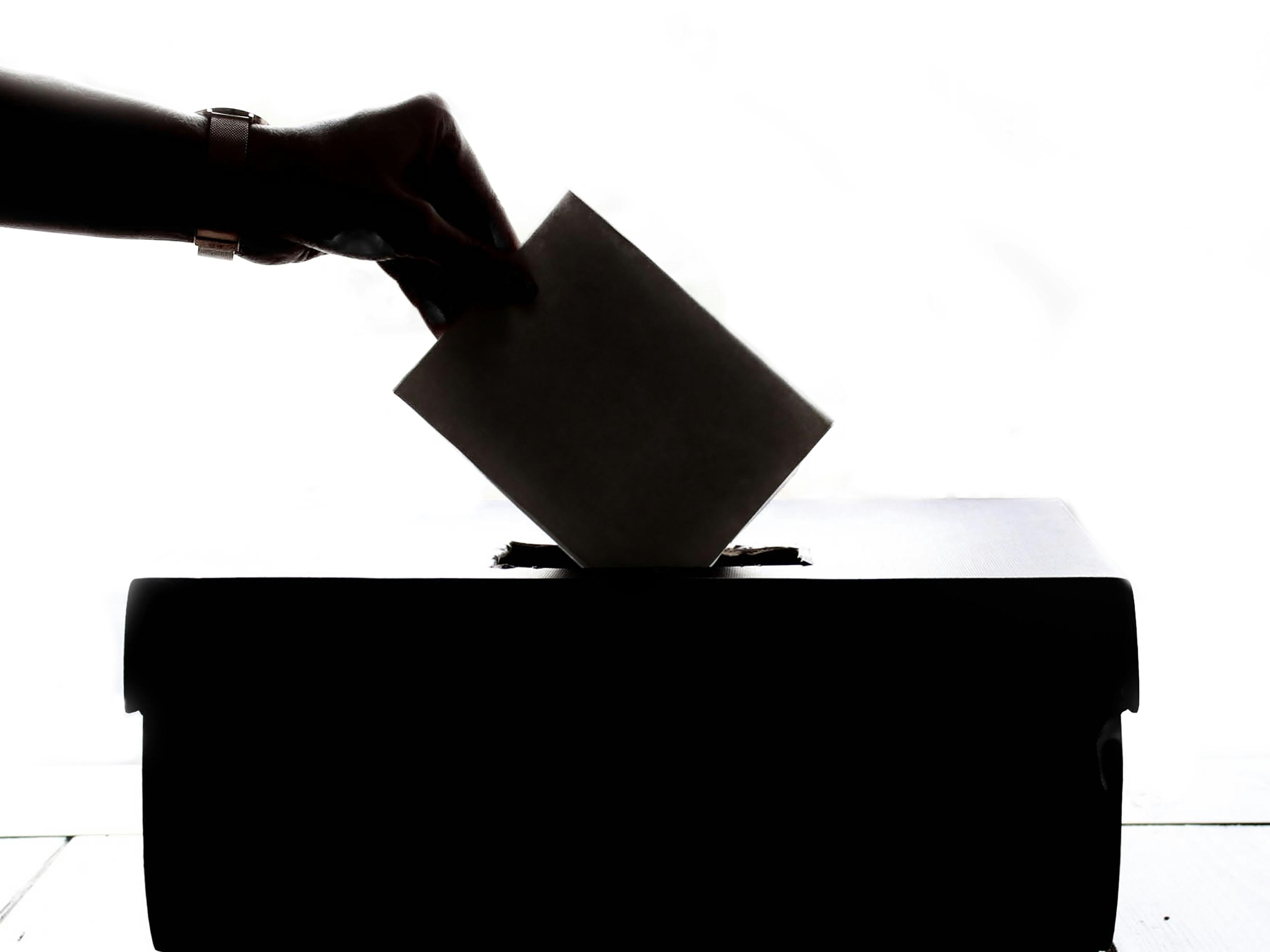 person placing envelope in ballot box